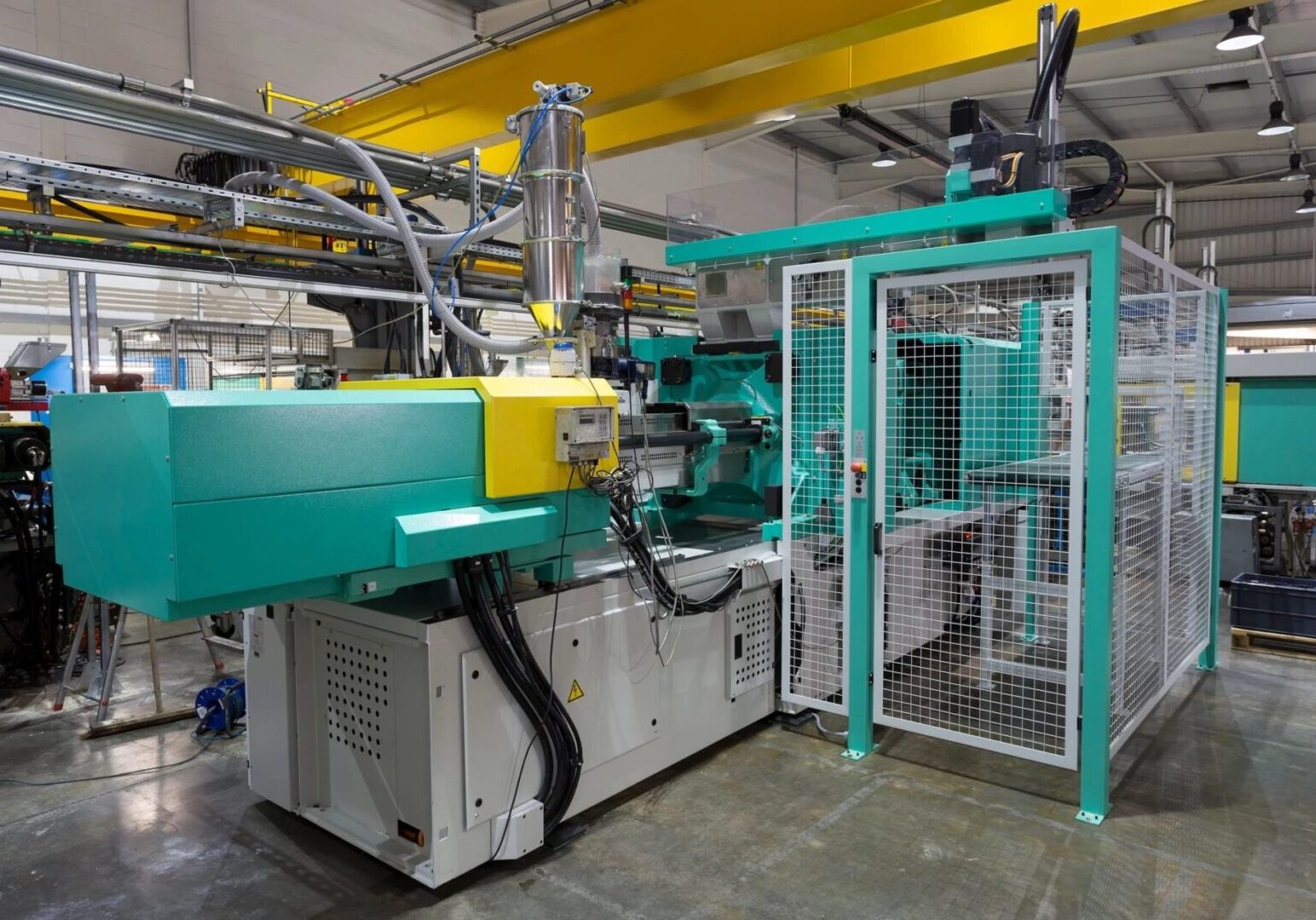 A machine in a factory with wires hanging from the ceiling.