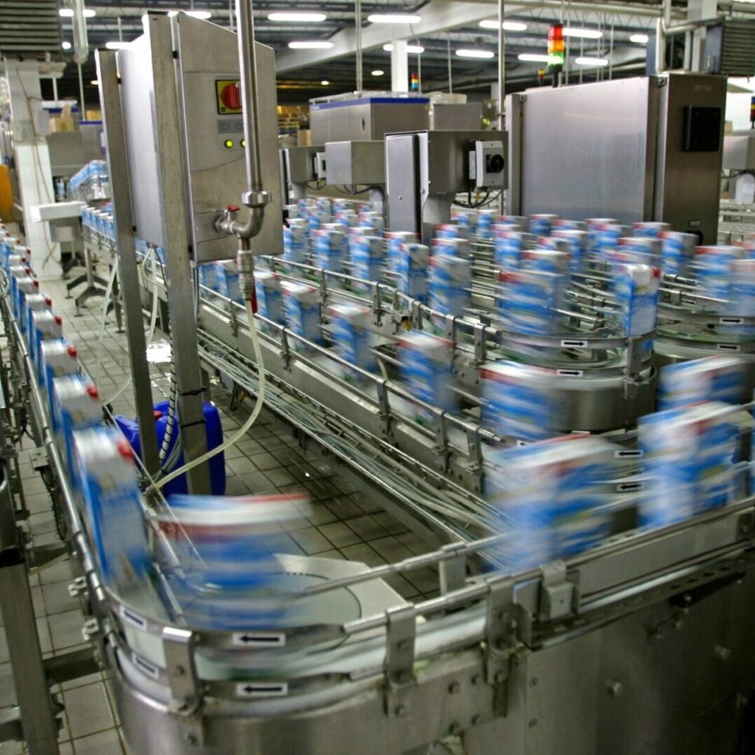 A factory with many cans of milk on the conveyer belt.